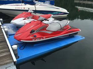 Side profile of a white-and-red and pure red water scooters parked at a marina dock