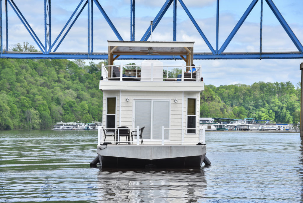 Open deck on the bow of a cream houseboat in the middle of a body of water