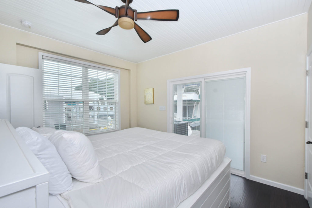 Cream-colored bedroom with a white bed and a brown ceiling fan