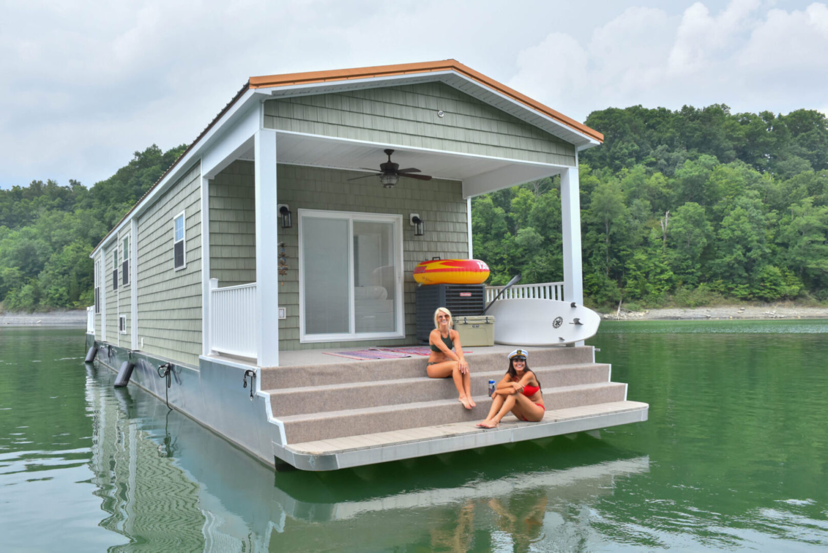 Two women in swimsuits relaxing in the stair steps of the houseboat’s stern area
