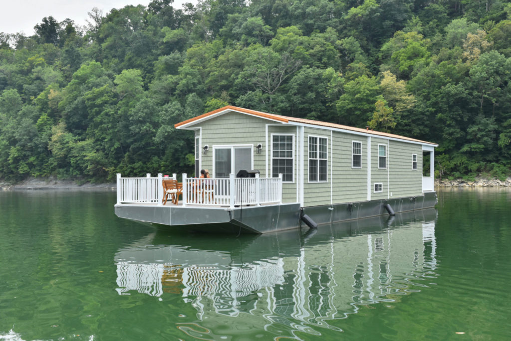 Open deck on the bow of a green houseboat in the middle of a body of water