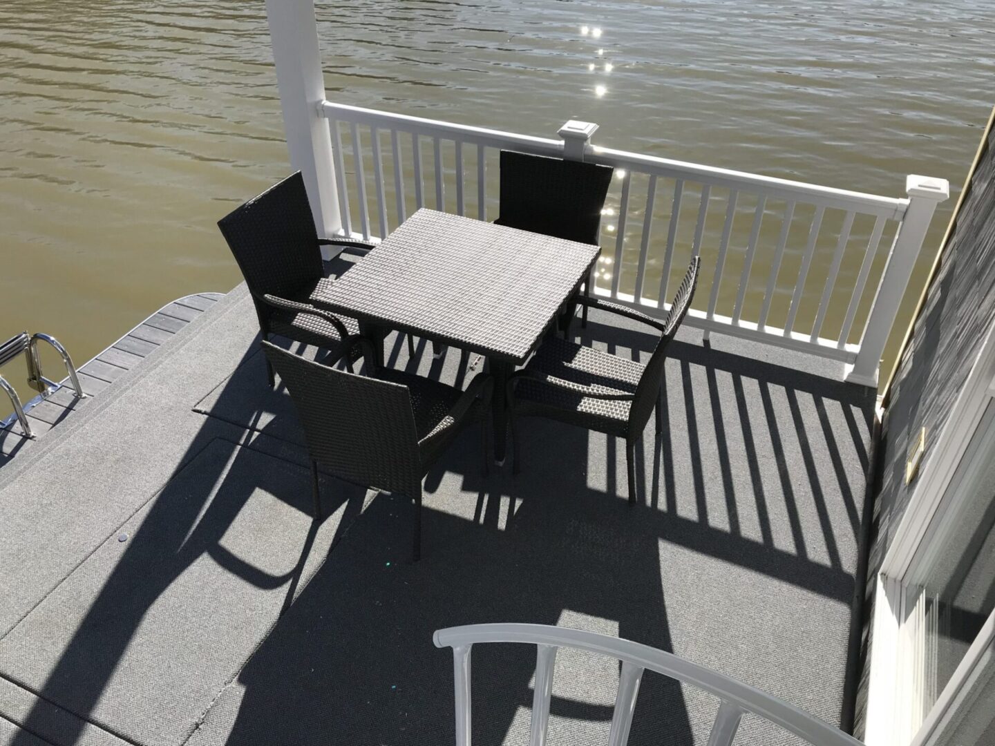 A black woven dining set in the stern area of a houseboat