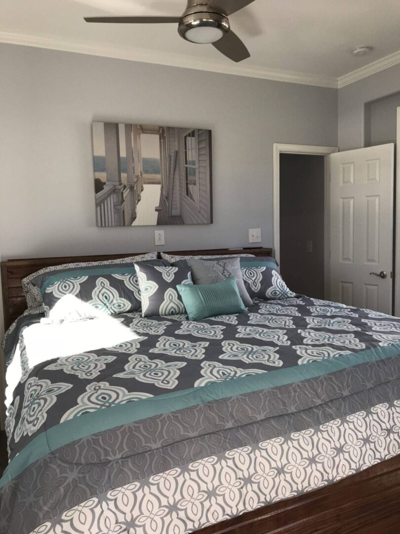 Light grey bedroom with a houseboat artwork above a bed with dark grey bedsheets and white designs
